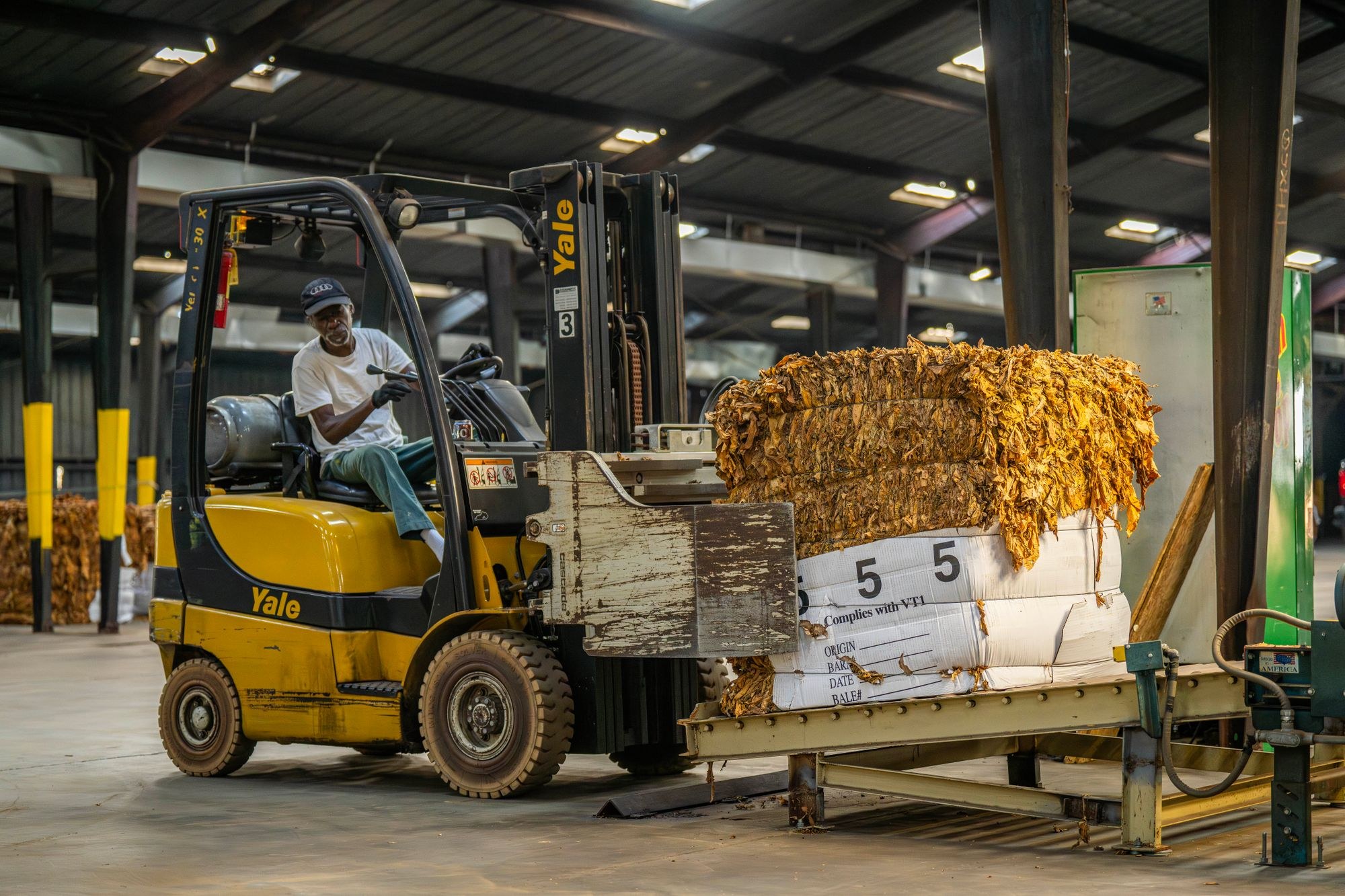 Forklift operator moving bundled material inside an industrial building