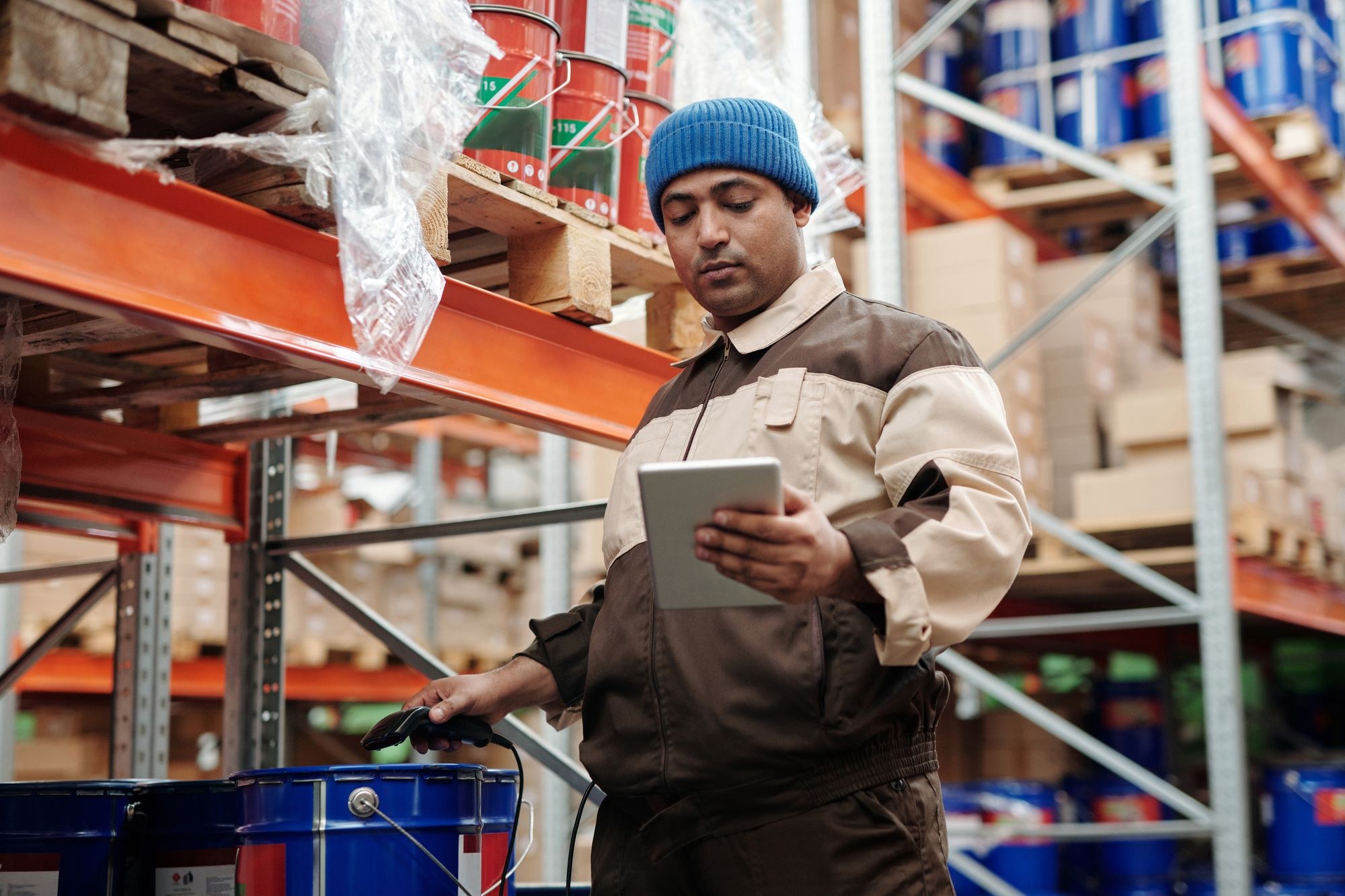 Warehouse employee using a tablet beside stocked shelves